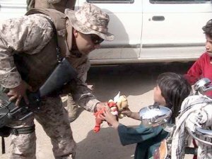 Soldier in Afghanistan offers a Beanie Baby to an Afghani child. This Beanie Baby was donated by AnySoldier supporters. Photo used courtesy AnySoldier.com